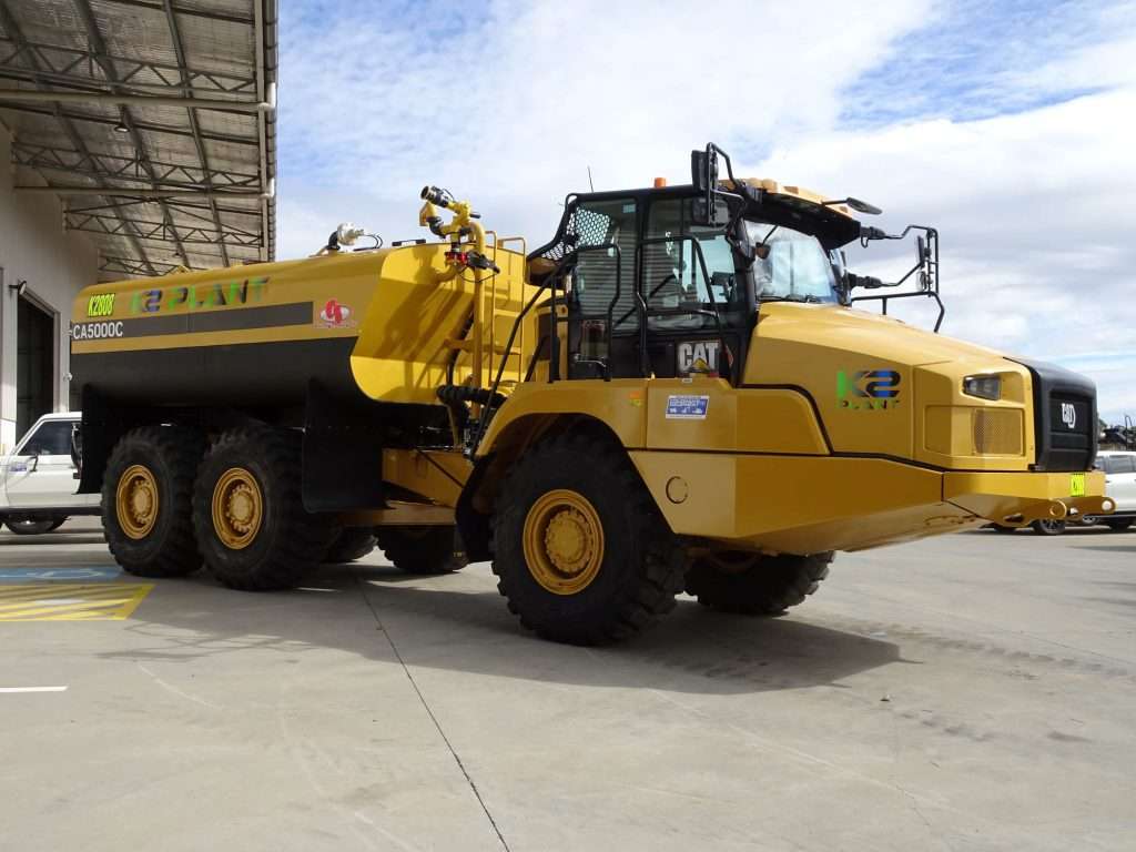 Yellow water truck parked on concrete.